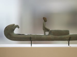Partial view of a bronze figurine of a man kneeling on a boat, on display in the Kelsey Museum’s Egyptian galleries.