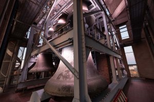 Large carillon bells hanging from a steel structure in two tiers.