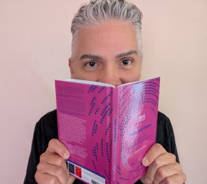 Person looking up behind a magenta book cover.