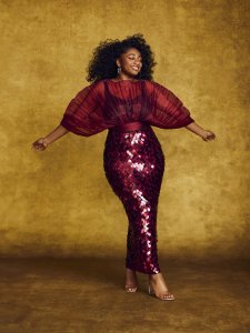 Woman in dark red sparkly dress with arms held out