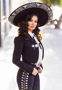 Young woman in black and white mariachi costume wearing black hat