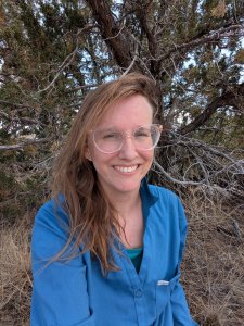 Woman in glasses and a blue shirt smiles at the camera