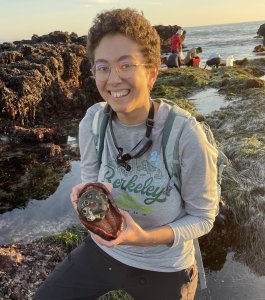Woman in glasses smiles at the camera from a tide pool while