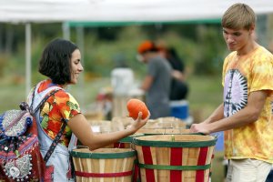 Two students select produce from bushel baskets.