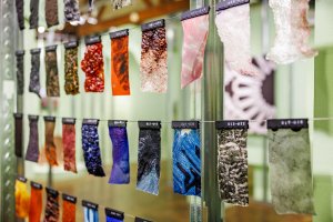 Samples of multi-colored fabrics and materials hung on tiered wires.