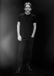 Standing studio portrait of Steven Mackey wearing all black with a black background.
