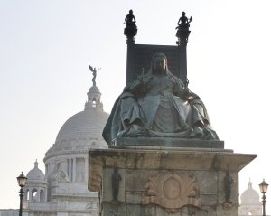 Image of an outdoor stone statue of Queen Victoria sitting on a throne