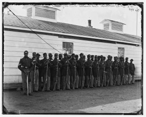 Photograph of Washington, 1862-1865, view of the defenses of Washington. Shows 27 African Americans in two lines with rifles resting on the ground.