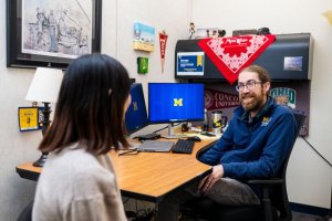 An advisor meets with a student in their office