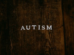 The words "autism" in white on a wooden table