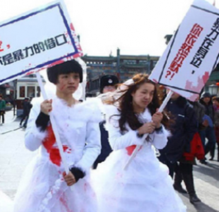Domestic violence protesters wearing wedding gowns with blood carrying signs