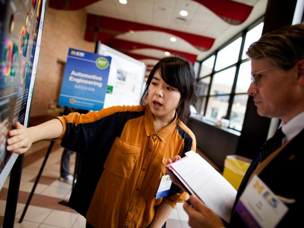 Student explains project at graduate symposium
