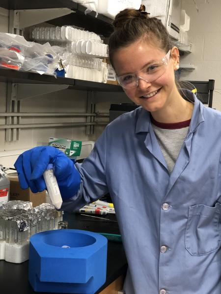 student wearing ppe holding test tube in lab setting
