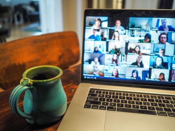 Blue mug next to laptop featuring a videoconference meeting