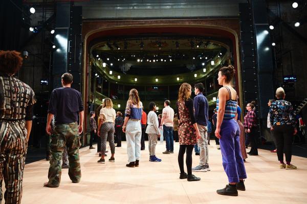 Dozens of people standing on a stage, facing in different directions. Photo © Manuel@DARC.