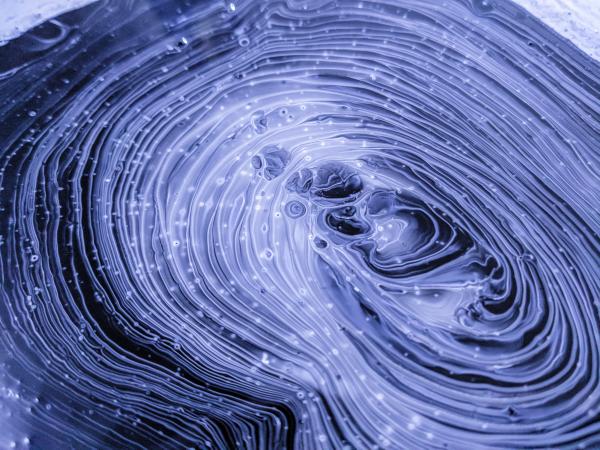 This experimental painting features swirls of black, grey, purple, and white paint and looks like an abstract version of the human brain.