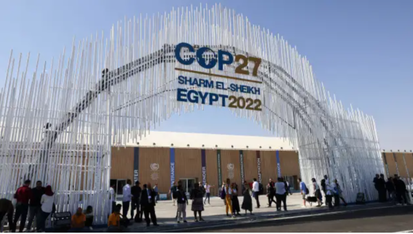 Entrance pavillion at the COP27 - a large white archway in front of a brown building
