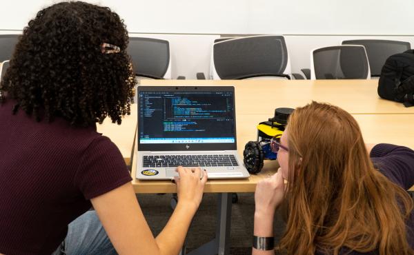 Two students work on programming a mobile robot