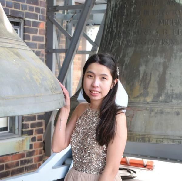 Zoe Lei poses with two large bronze Bells from the Baird Carillon