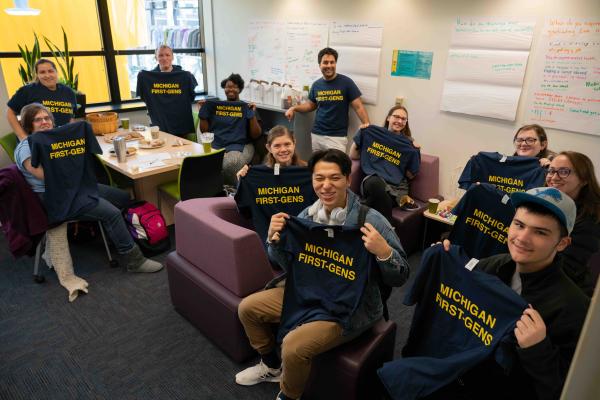 Students holding shirts that say "MICHIGAN FIRST-GENS" in the First-Gen Gateway space