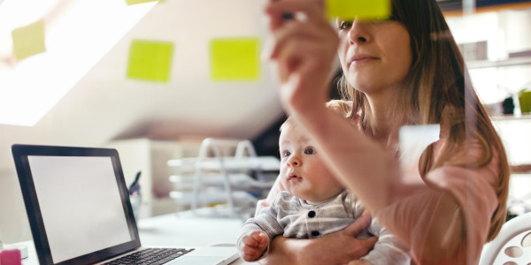 Working mother at desk with laptop and baby
