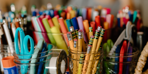 Jars of multi-colored markers, pencils, and scissors