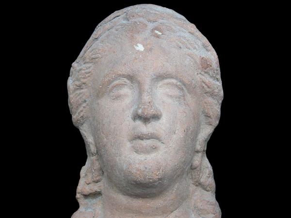 Ceramic votive head of a woman wearing earrings.