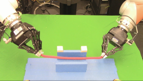 Two robot manipulators hold a rope between an obstacle.