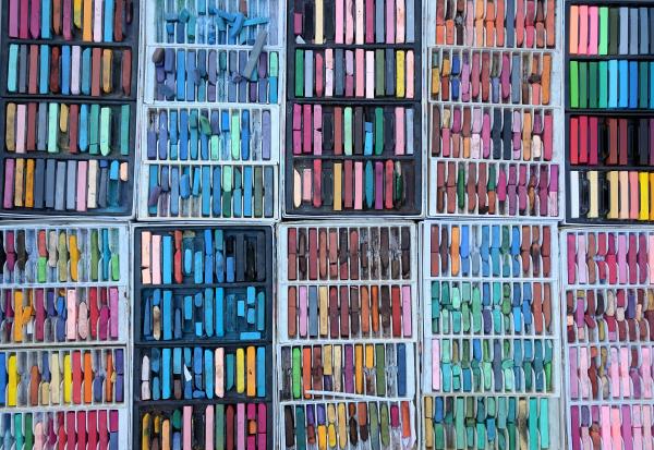 A wide variety of brightly colored pastel sets are lined up in rows, filling the image