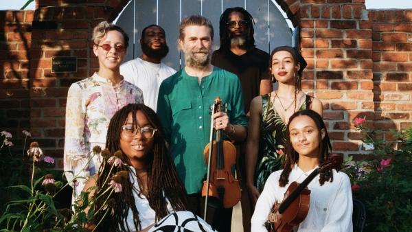 the White Flowers musical group in front of a brick building holding instruments