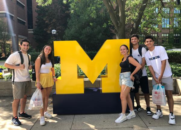 Students standing next to a giant maize and blue M.