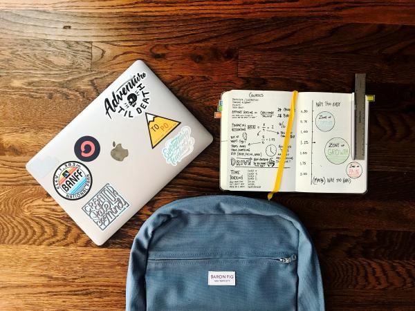 Backpack, laptop, notebook and pencil on a wood table