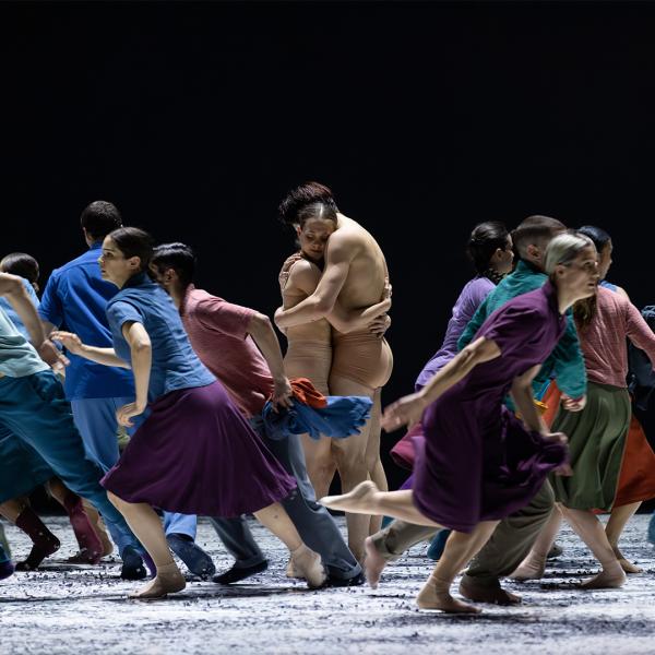 Man and woman hugging with people running around them