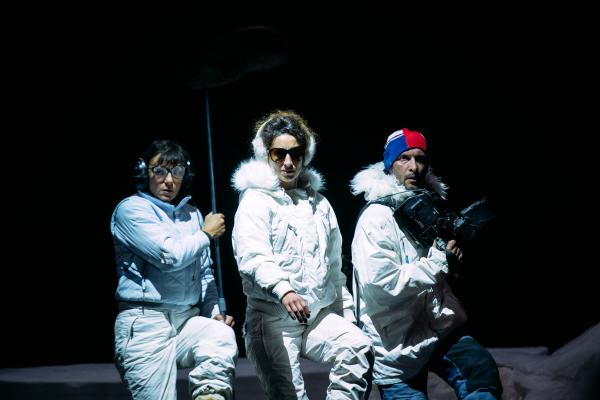 3 people dressed in snow gear on dark stage