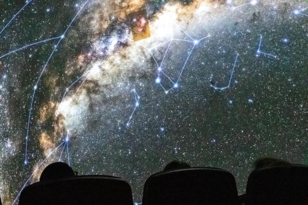 Visitors at a planetarium show looking up at the lighted dome.
