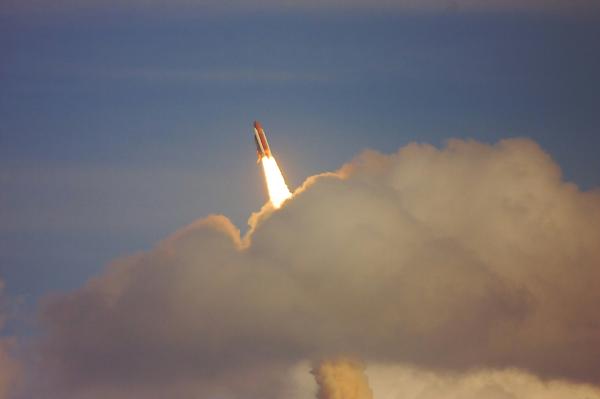 Rocket launching through clouds into sky