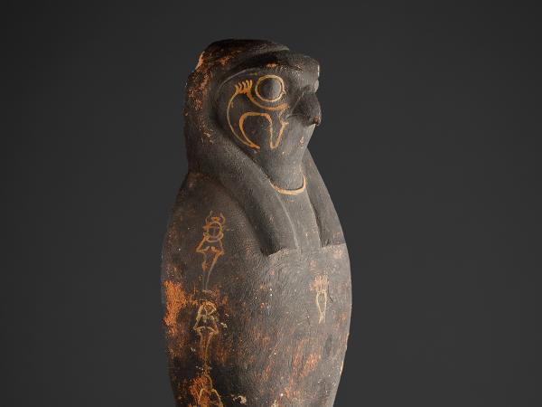 The head and shoulders of a corn mummy coffin depicting the falcon face of the Egyptian god Horus.