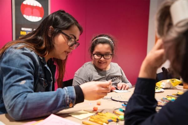 Visitors, gathered around a table, collaborate on a printmaking project at Stamps Gallery
