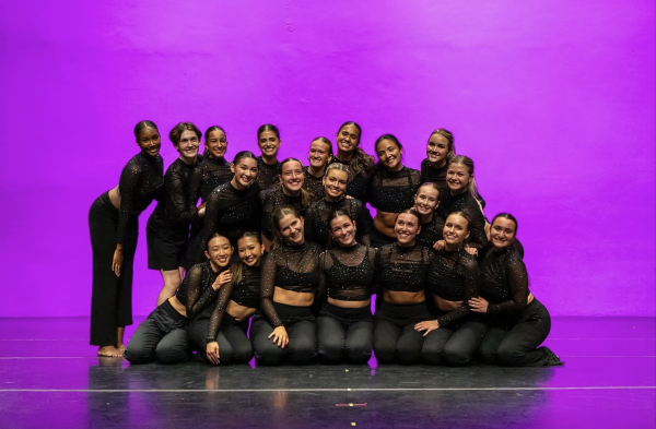 Dancers in black posing in front of purple background