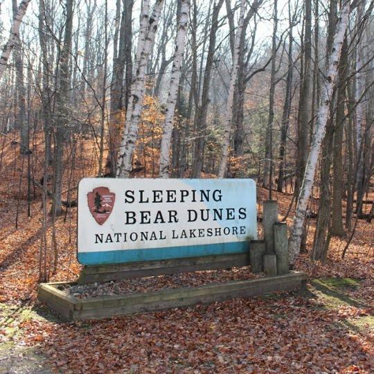 Sleeping Bear Dunes National Lakeshore Park Sign nestled between heavily wooded area