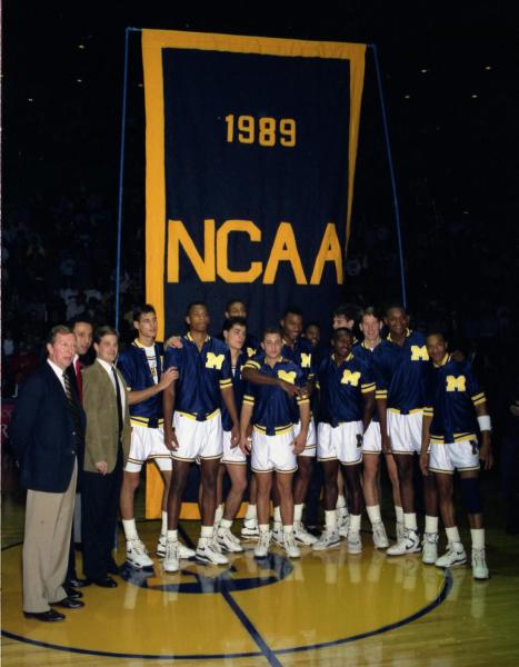 The 1989 U-M basketball team stands in front of a navy banner with "1989 NCAA" in maize.