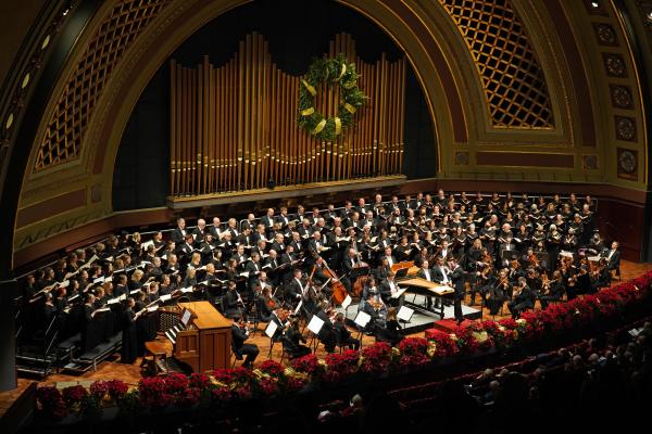 Interior of Hill Auditorium with orchestra and chorus on stage and a wreath hanging above the organ pipes