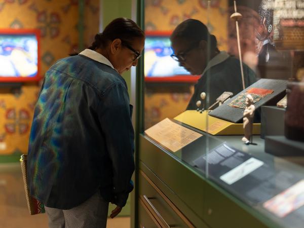 A visitor looks into a case displaying objects relating to textile production (such as a fragment of fabric, a spindle, whorls, and a weaving comb) on display in the Kelsey Museum’s Byzantine and Islamic gallery.