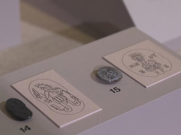 Close-up of two Seleucid seals at the Kelsey Museum. Each seal is displayed next to a drawing showing the details of its carvings.
