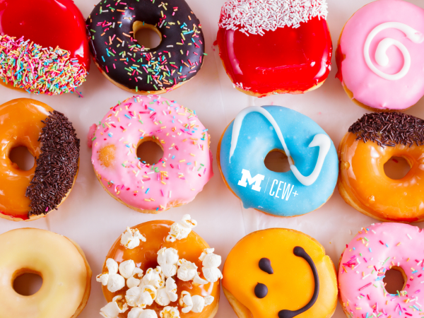 Colorful donuts decorated with various toppings including sprinkles, icing, popcorn, chocolate, and smiley face designs.
