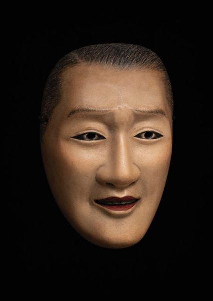 A photo of a Japanese noh mask against a black background.