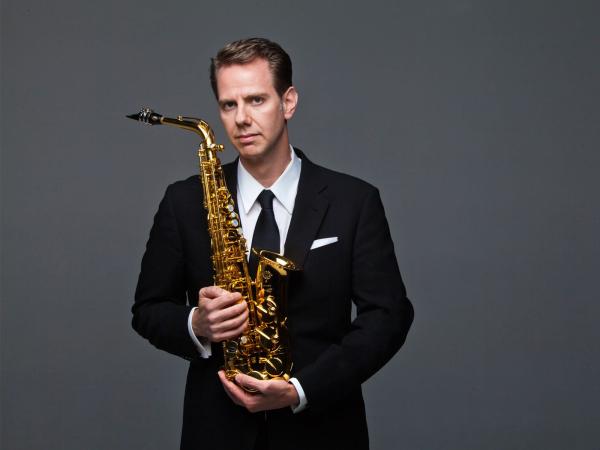 Studio portrait of Timothy McAllister holding his saxophone.