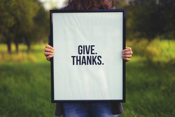 Person holding a sign that says "Give Thanks".