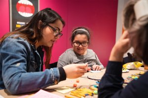 Visitors, gathered around a table, collaborate on a printmaking project at Stamps Gallery