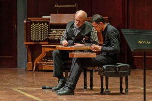 Two musicians on a stage play the santour.